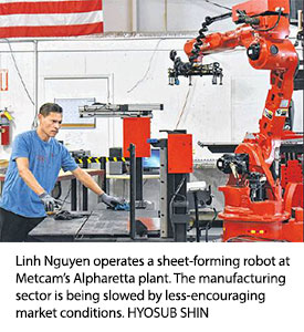 Linh Nguyen operates a sheet-forming robot at Metcam's Alpharetta plant. The manufacturing sector is being slowed by less-encouraging market conditions. HYOSUB SHIN